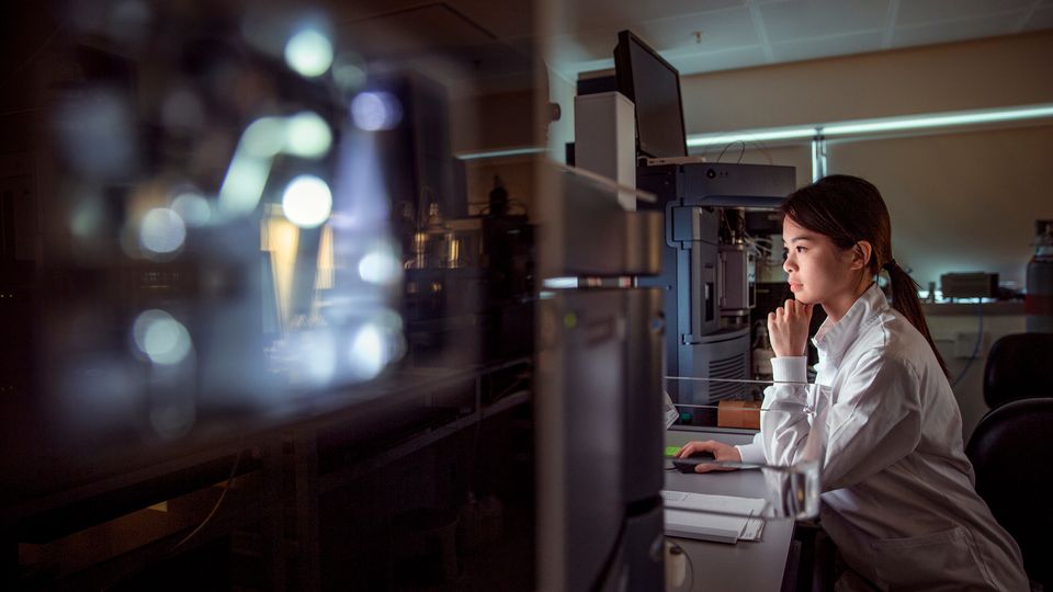 Scientist in a laboratory working with advanced imaging equipment, analyzing data on a computer for research purposes.