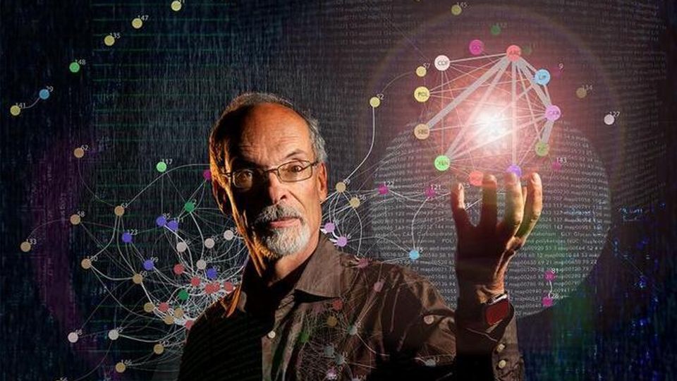 A man with glasses stands in front of a digital network diagram, holding up his hand with a glowing network sphere above his palm.