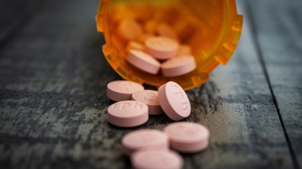 An orange pill bottle with white aspirin pills spilling out.
