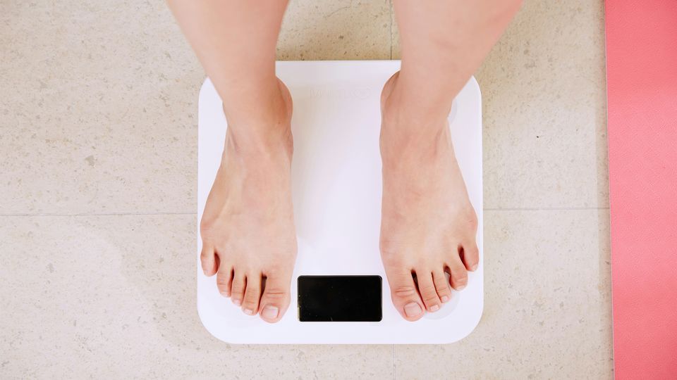 A person standing on a set of scales measuring weight loss.