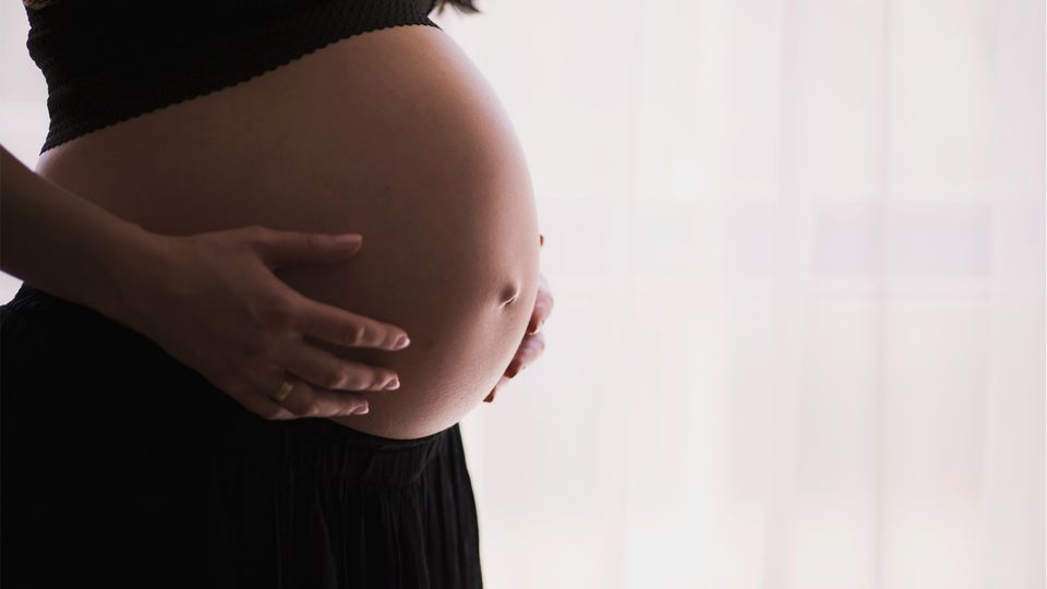 A pregnant women holding her stomach.