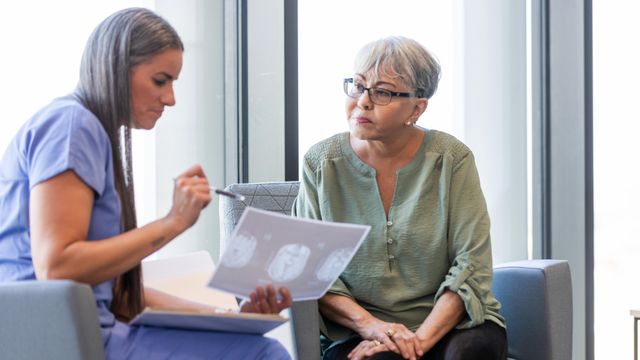 Doctor reviewing brain scan results with an older woman during an Alzheimer’s diagnosis consultation. 