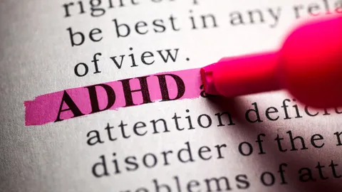 The word ADHD highlighted in pink on a printed page with a marker.