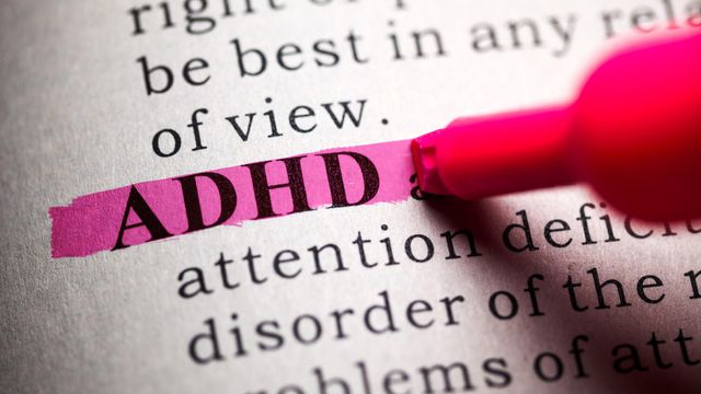 The word ADHD highlighted in pink on a printed page with a marker. 