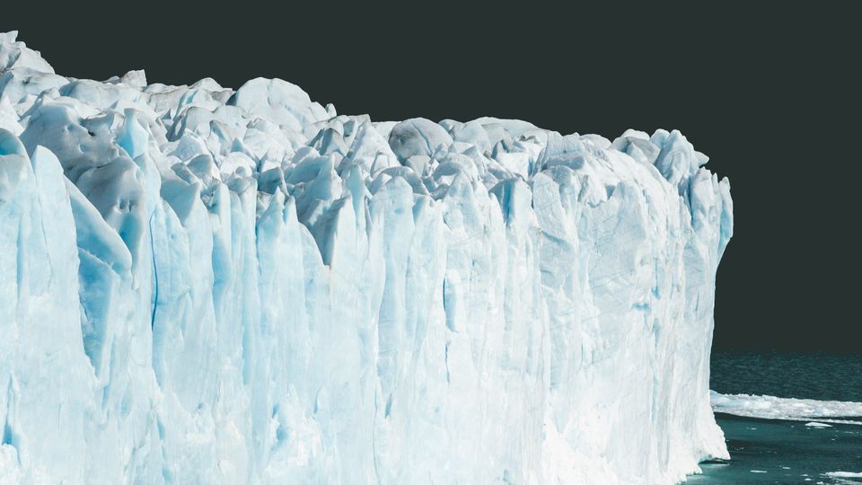 The high white wall of a glacier. Background sky oddly grey and black.