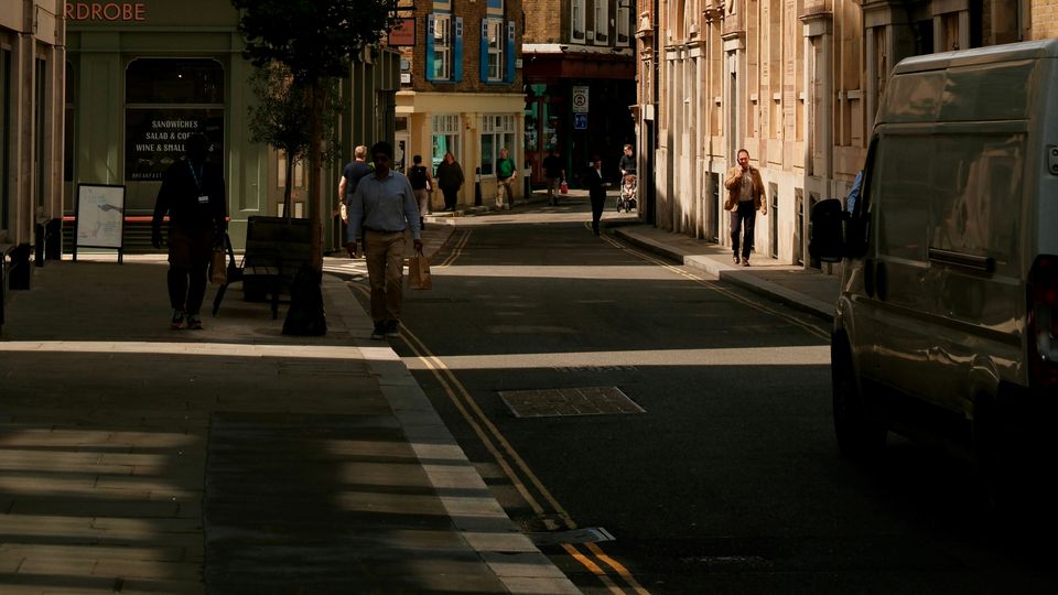 A narrow lane in London, shadows spreading across the road and path. Sunshine stark higher up.