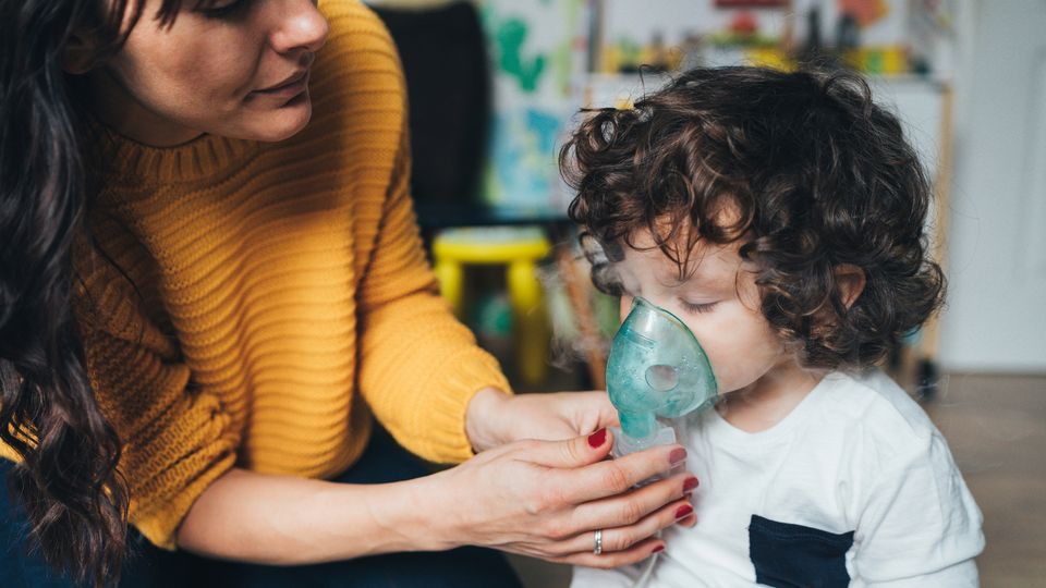 A mother helping her child use an inhaler to combat an asthma attack.
