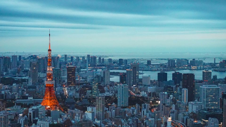 A Tokyo skyline, all buildings as grey as the sky bar the Tokyo Tower in red.