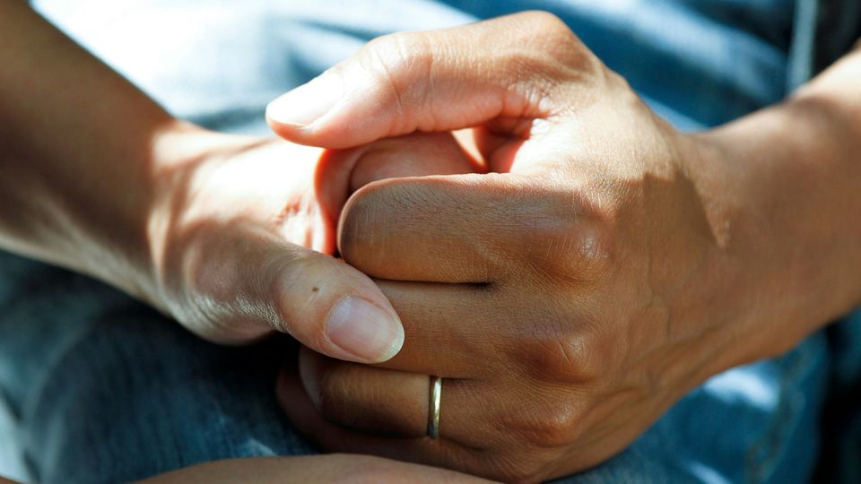 Two hands clasp in a clear, staged act of support.
