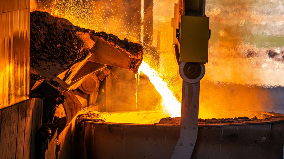 Molten ore flows into a vat in a steel production factory.