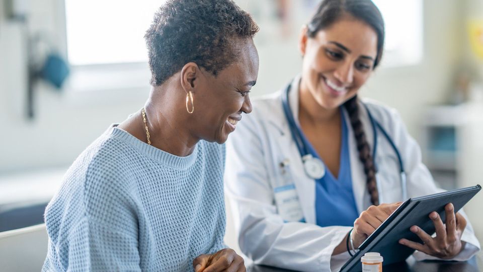 A female doctor talking to a cancer patient receiving treatment in hospital.