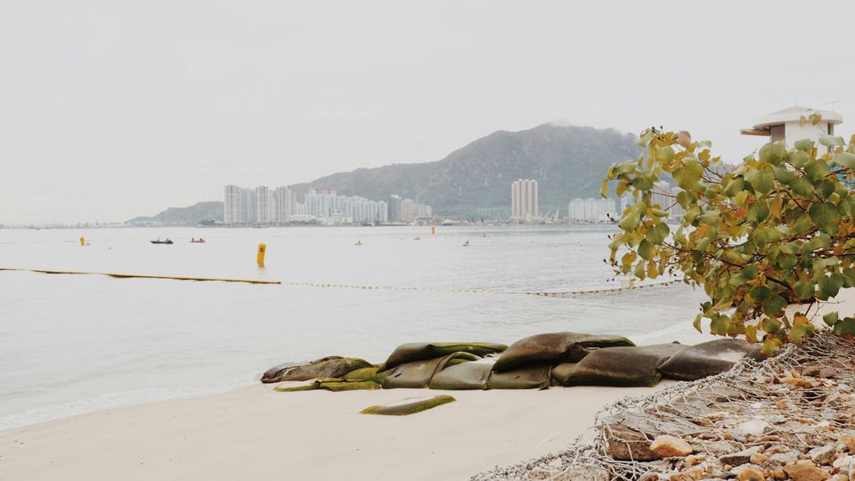 A view of Hong Kong's tower blocks across the sea at a beach.