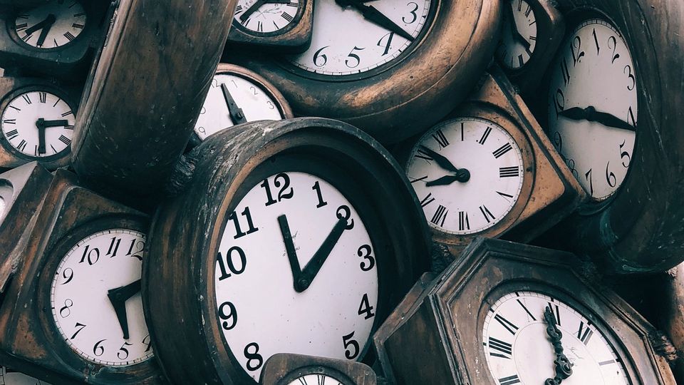 Wooden clocks with white faces showing different times, symbolizing the circadian rythym.