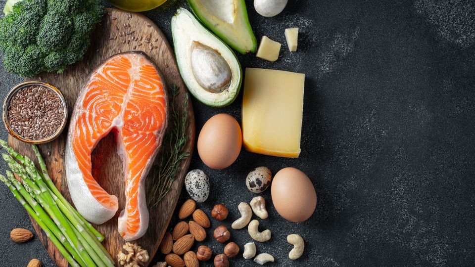 Flat-lay photograph of eggs, salmon, nuts and seeds, all part ok a keto diet.