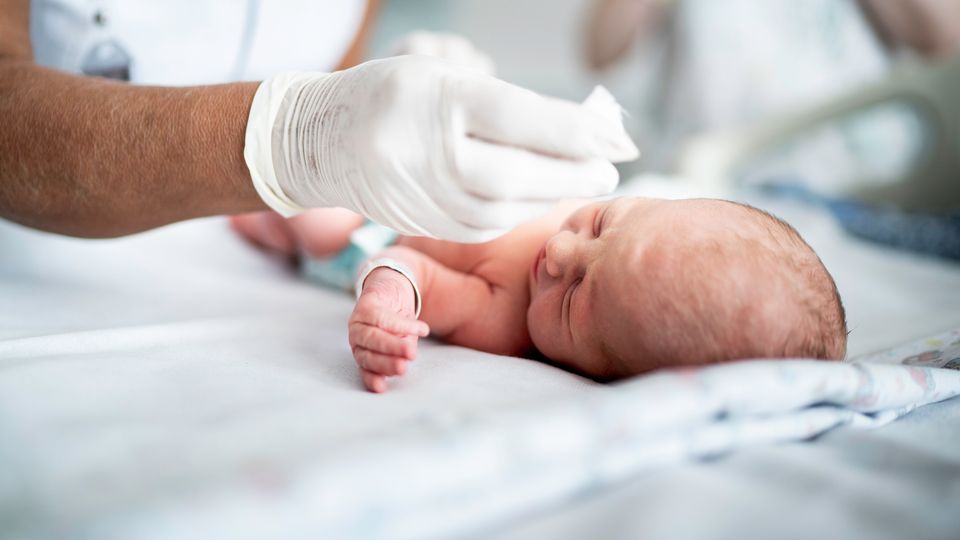 Newborn in hospital receiving care, representing early genomic screening in infants.