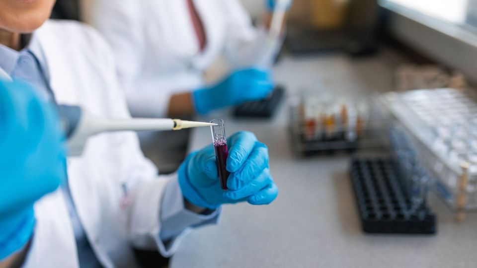 Scientist pipetting sample into test tube for PCR analysis in a laboratory setting.