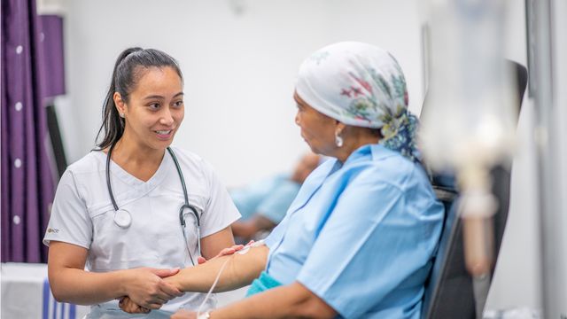 A female cancer patient receiving an IV talking to a female doctor. 
