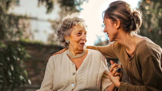 An old woman and a younger woman in a garden. 