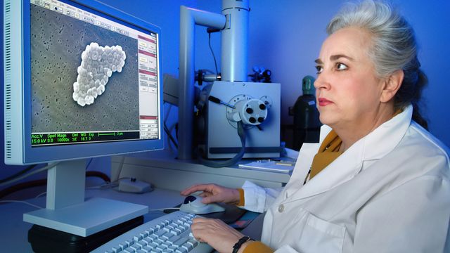 A microbiologist using an electron microscope to scan a specimen of bacteria. 