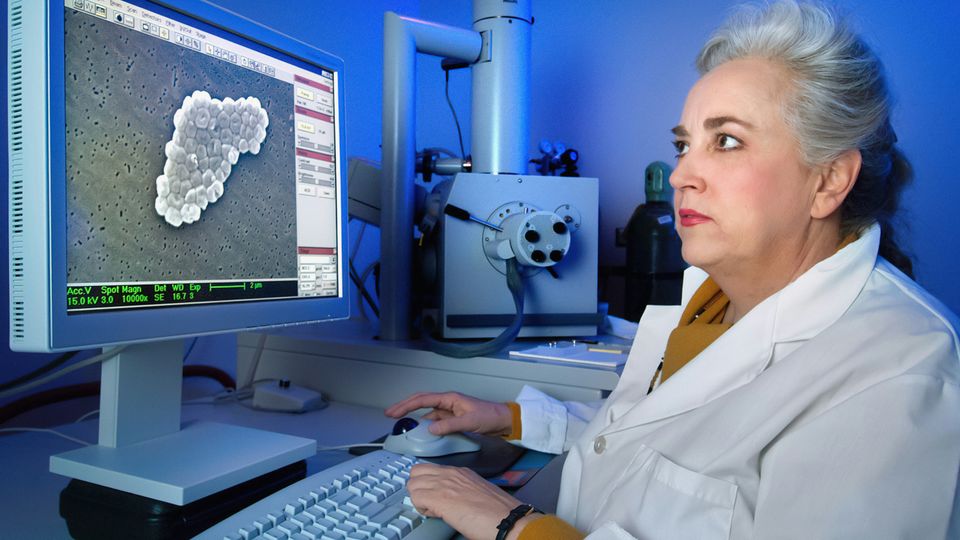 A microbiologist using an electron microscope to scan a specimen of bacteria.