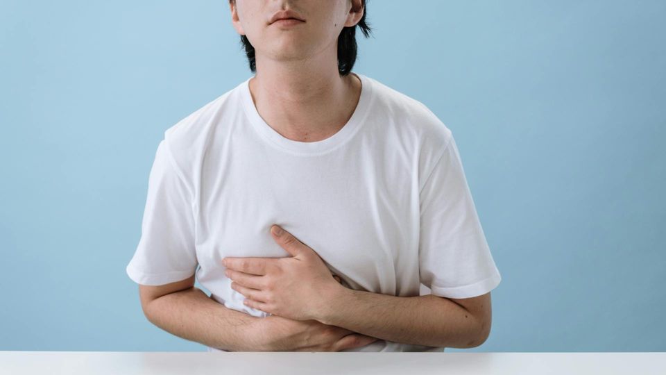Man clutching his abdomen in discomfort, illustrating symptoms of IBS (Irritable Bowel Syndrome).