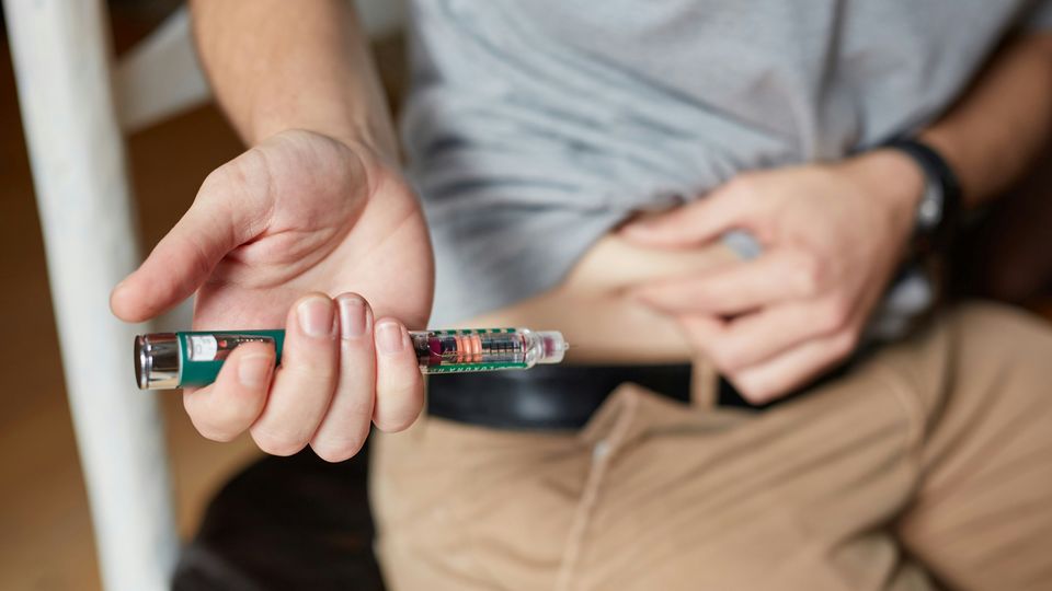 A man preparing to administer an insulin injection in his stomach.