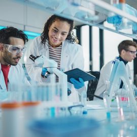 Researchers in a modern lab collaborating with a microscope, demonstrating sustainable laboratory practices 