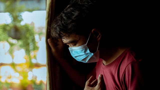 Man wearing blue face mask, coughing. 