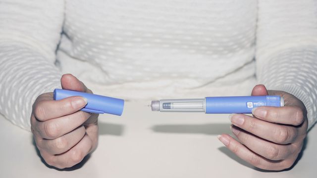 Individual holding a weight loss drug pen unsheathed. 