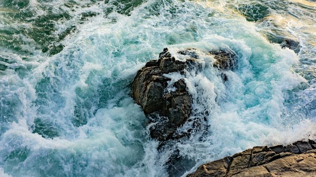 Waves crashing over a large rock. 