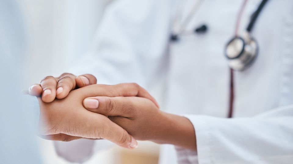 Close up of doctor and patient holding hands.