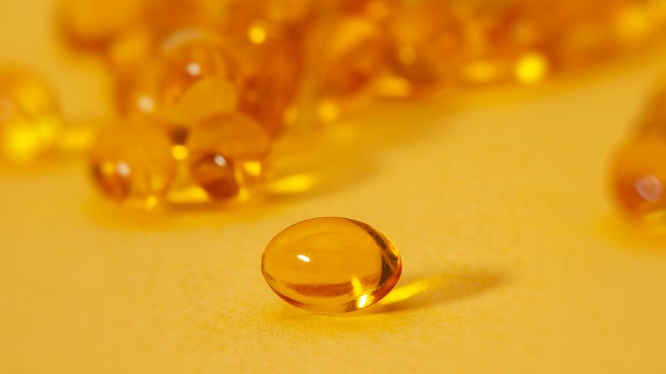Yellow omega-3 pills on a yellow background.