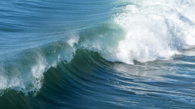 The crest of an ocean wave beginning to crash. 