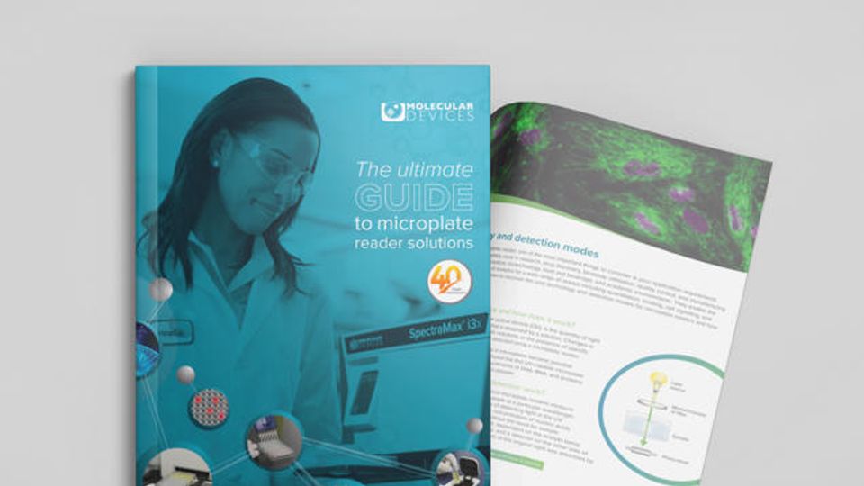 Scientist wearing safety goggles reviewing a guide on microplate reader solutions in a laboratory.