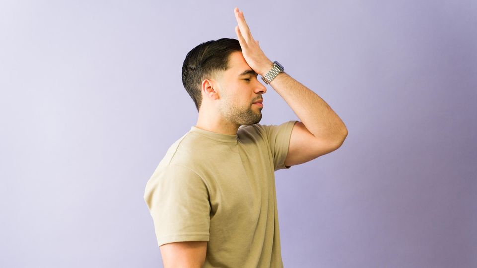 Man slapping his forehead in frustration, expressing a moment of forgetting or regret.