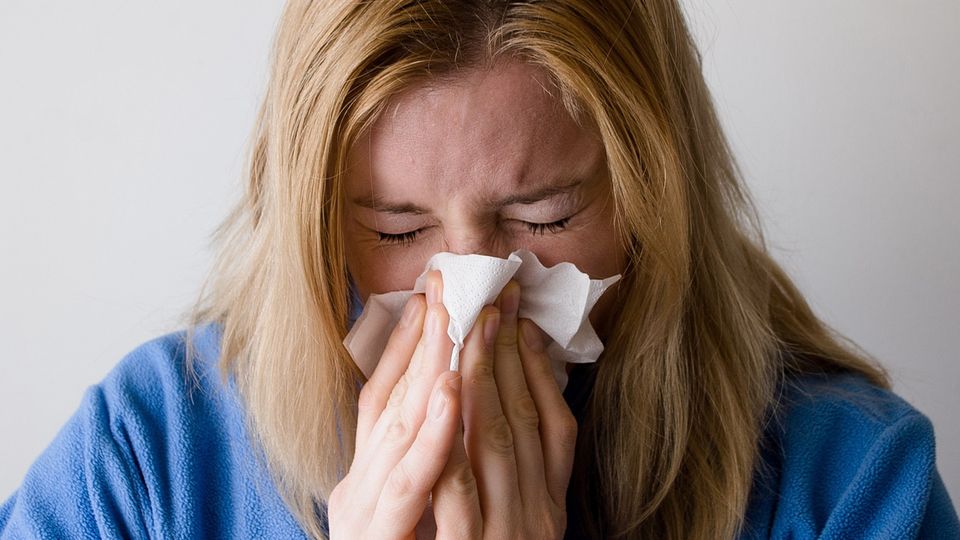 A woman with a viral infection blows her nose into a tissue.