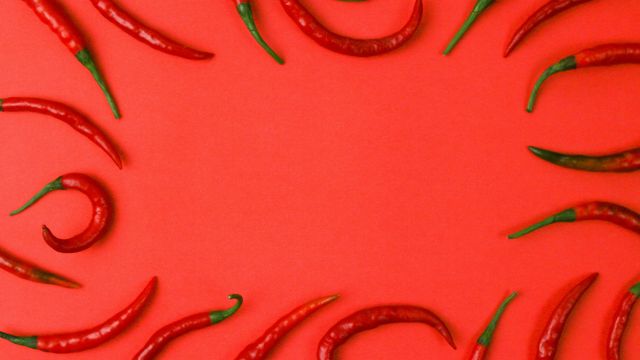 A red background with red chili peppers spread around the outer edge of the picture. 