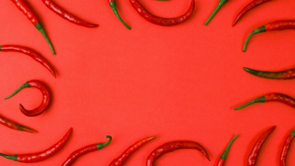 A red background with red chili peppers spread around the outer edge of the picture.