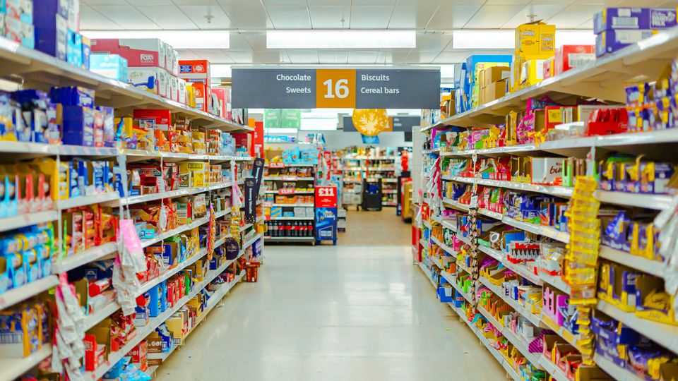 A photograph looking down a supermarket snack and sweets aisle. 