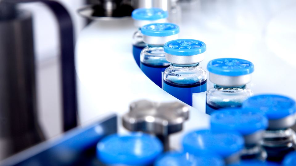 Vaccine vials on a production line, representing child vaccine development in a lab setting.