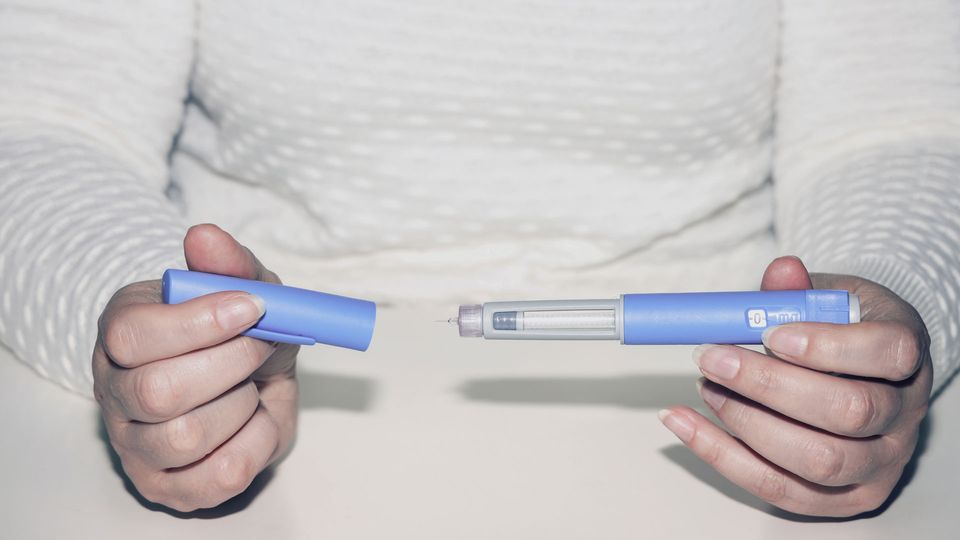 Individual holding a weight loss drug pen.