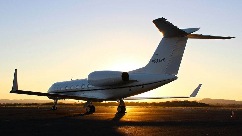The rear-view of a private jet on a runway at sunrise.