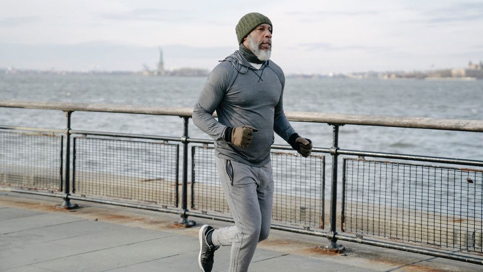 A man with a gray beard runs along the riverfront.