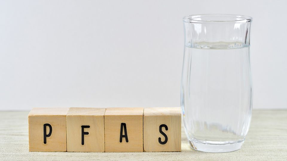 A jug of water next to some blocks spelling out the word PFAS.