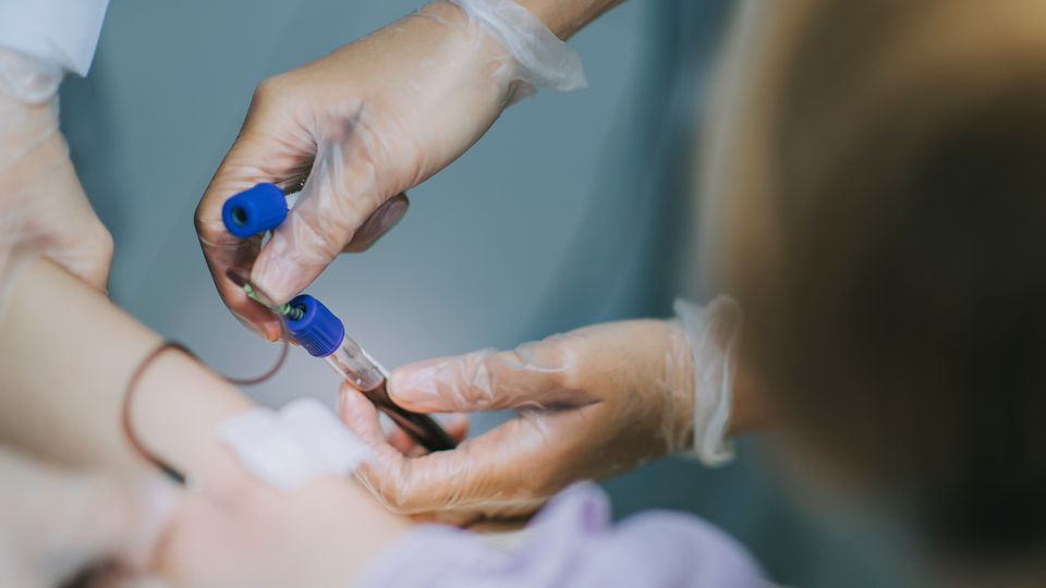 Healthcare worker drawing blood from a patient for immunological signature analysis.