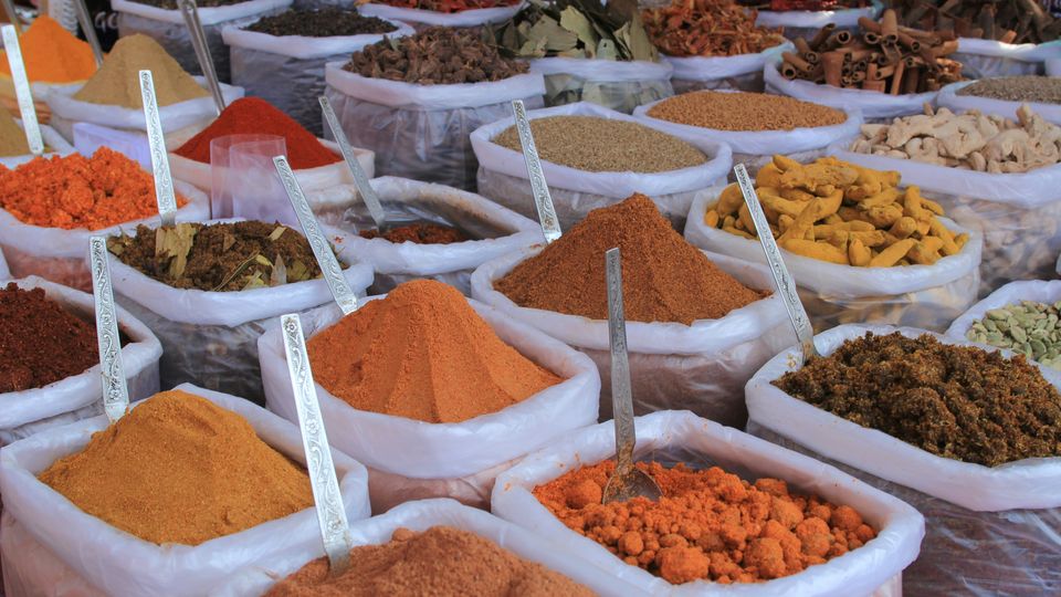 Large boxes of ground spices and seeds for sale in an Indian spice market.