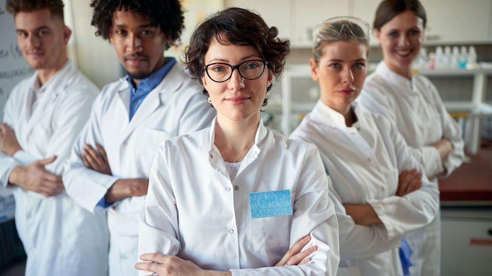 Scientists wearing white coats looking at camera with arms crossed.