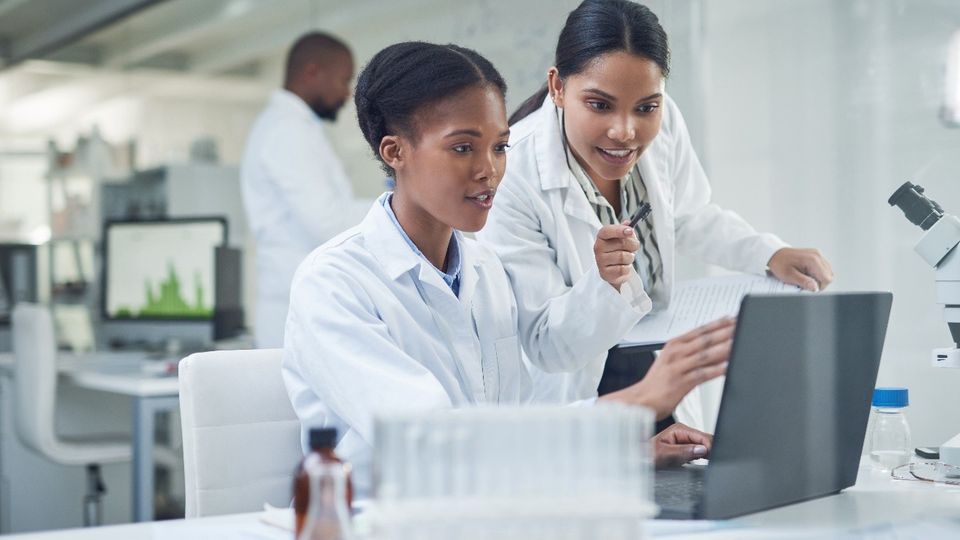 Scientists collaborating at a laptop in a lab, reflecting ACD/Labs’ 2025 software upgrades that enhance digital R&D workflows.