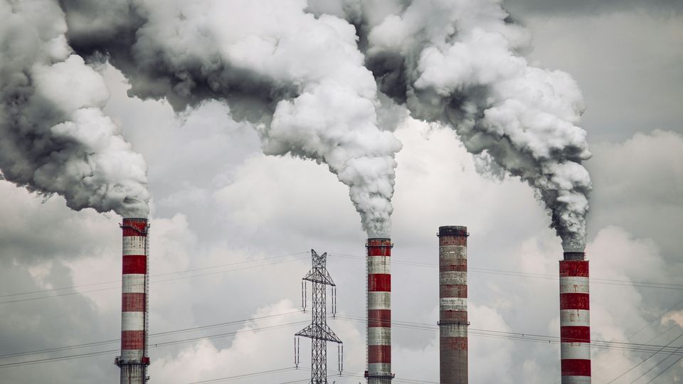 Smoke billowing from chimneys at an industrial site, illustrating gas emissions.