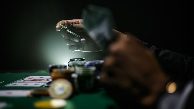 Close-up of hands placing poker chips on a table surrounded by cards and stacks, symbolizing impulsive behavior. 